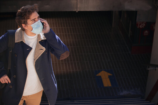 Man with facemask holding a bag and talking on the phone