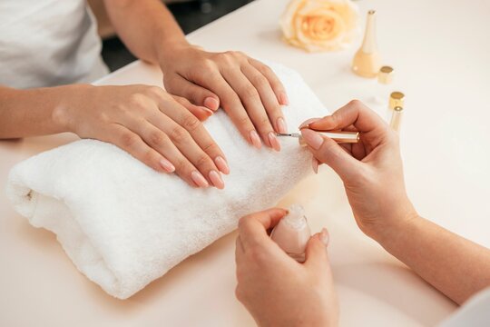 Manicurist applying nail polish to customers nails