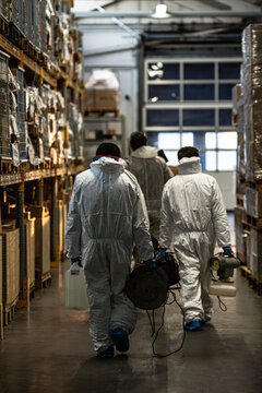 Men in PPE holding sanitizing machines