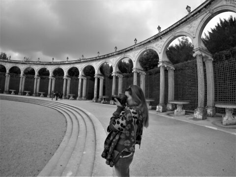 Monochrome photo of woman holding a camera at the Palace of Versail, France