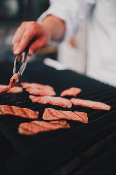 Person cooking meat on grill