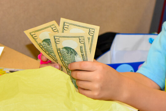 Person holding three 10 dollar bills