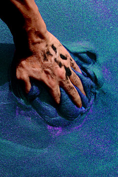 Persons Hand On Blue Sand