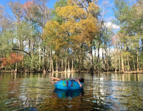 Person sitting on floater in lake between trees
