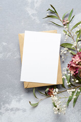 Wedding invitation or greeting card mockup with eucalyptus, gypsophila and hydrangea decorations. Card mockup with copy space on grey. © nikavera