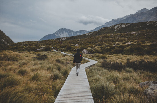 Person walking on a wooden walkway near mountains