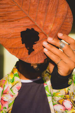 Portrait of a man covering his face with yellow tree leaf