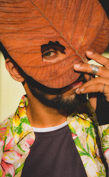Portrait of a man covering his face with yellow tree leaf
