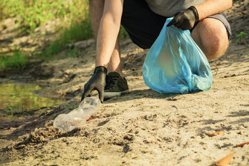Man volunteer gathering garbage in forest. Environment protection pollution problems
