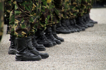 Cropped image of soldiers with leather boots and camouflage uniform