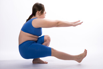 a girl of European appearance in a blue suit is engaged in fitness or yoga. White background. not a perfect figure. Sports training. Coordination exercise
