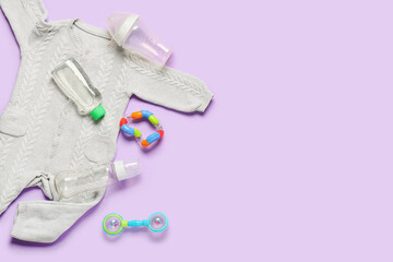 Stylish baby clothes with toys and bottles on color background