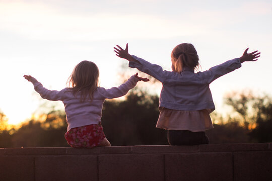 Two children raising their arms outdoors