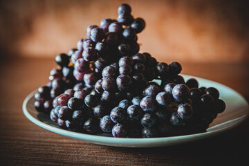 juicy fresh bunches of ripe wine grapes on a solid plate, contrast photo