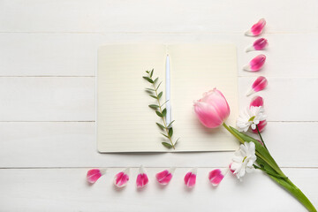 Composition with open notebook, pen and flowers on light wooden background
