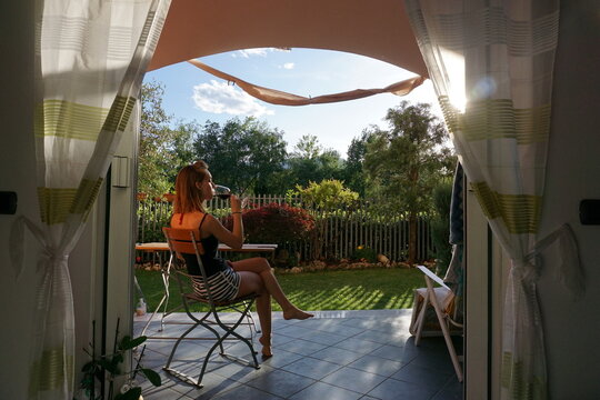 Woman dinking red wine in a house garden