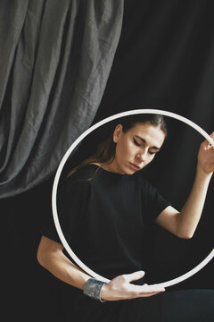 Woman holding a Hella hoop beside black curtain