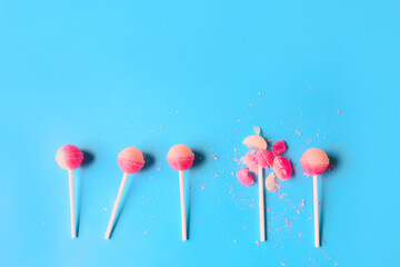 Broken lollipop among whole ones on color background. Concept of uniqueness