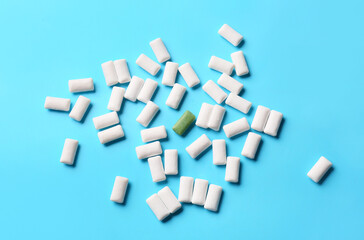 Green chewing gum among white ones on color background. Concept of uniqueness