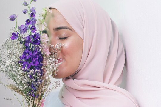 Woman in pink hijab smelling flowers