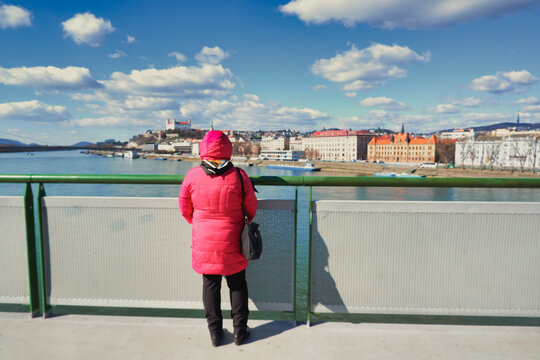 Woman in red jacket standing on bridge