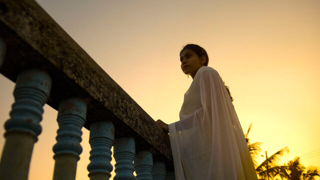 Woman in white dress standing on concrete bridge