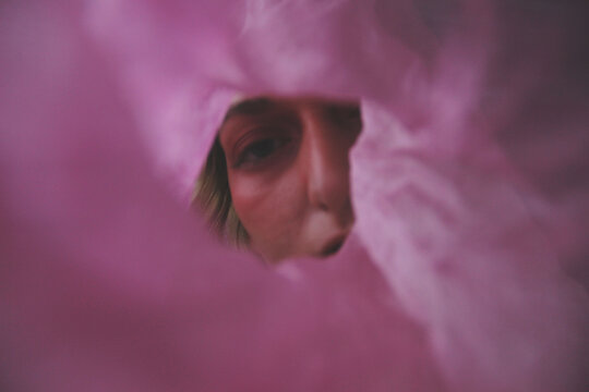 Woman looking through a hole in a oink textile