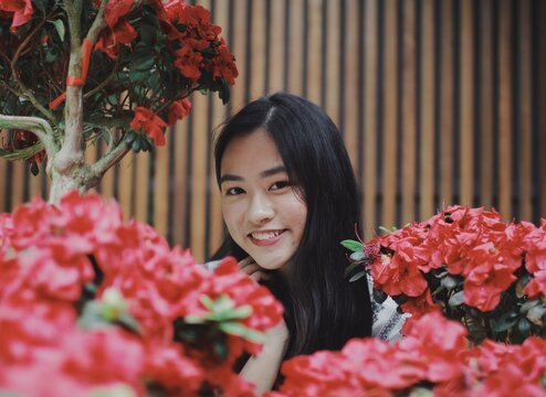 Woman smiling between red flowers