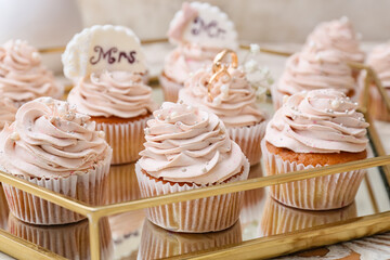 Tray with tasty wedding cupcakes on table