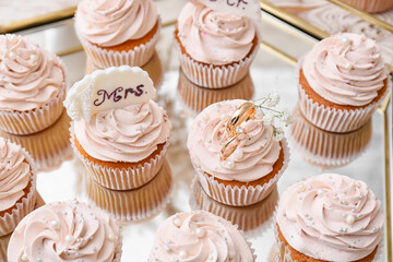 Obraz na płótnie Canvas Tasty cupcakes and wedding rings on tray