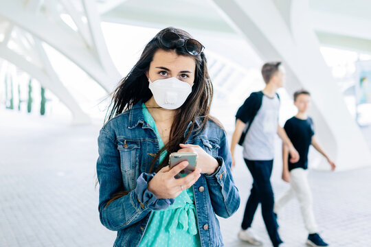 Woman with facemask using phone outdoor