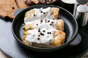 Baking dish with tasty stuffed cabbage rolls and sauce on table