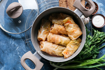 Pot with tasty stuffed cabbage rolls on color background