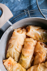 Pot with tasty stuffed cabbage rolls on color background, closeup