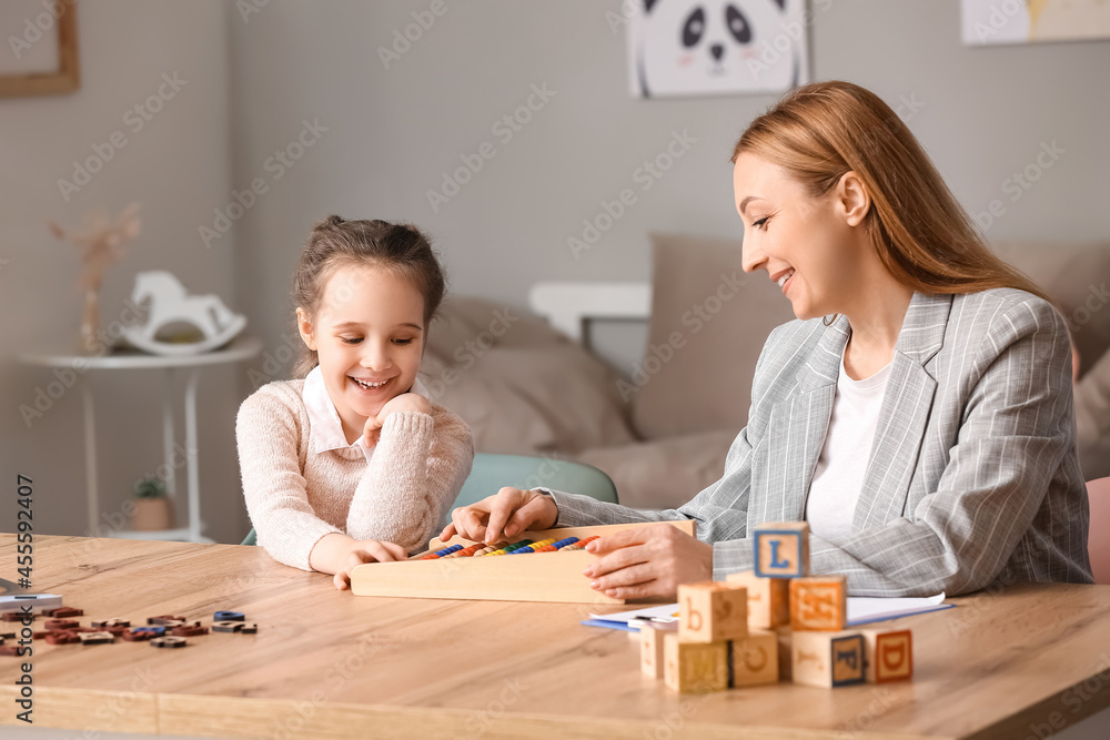 Wall mural female psychologist working with girl suffering from autistic disorder in office