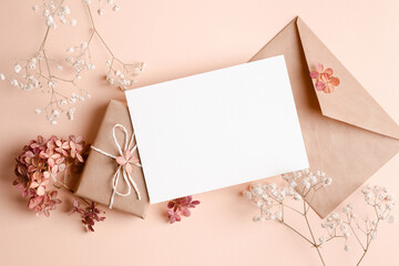 Greeting or invitation card mockup with gift box, hydrangea and gypsophila flowers decorations.