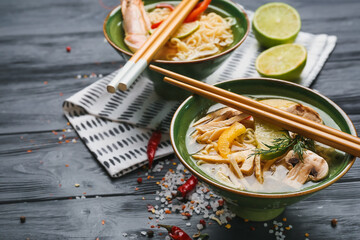 Bowls of tasty Thai soup on dark wooden background