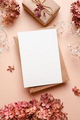 Greeting or invitation card mockup with gift box, dry hydrangea and gypsophila flowers decorations.