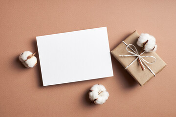 Invitation or greeting card mockup with gift box and natural cotton plant flowers decorations