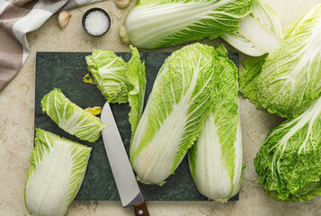 Board with fresh chinese cabbage on color background