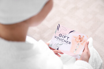 Young woman with gift voucher for massage at home - obrazy, fototapety, plakaty