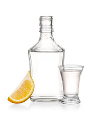 Bottle and shot of tasty tequila with lemon on white background