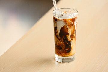 Glass of tasty ice coffee on table