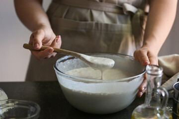 Fototapeta na wymiar Female chef preparing dough on kitchen table, closeup