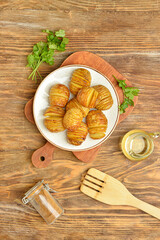 Plate with tasty baked potato on wooden background