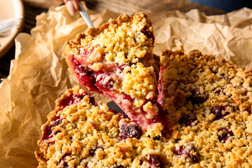 Taking piece of tasty cherry pie from parchment, closeup