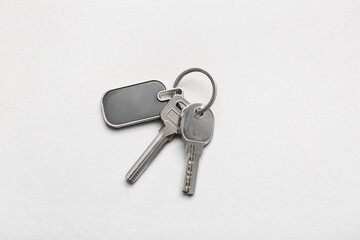 Keys with stylish keychain on light background
