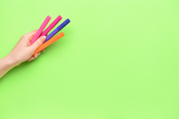 Naklejka premium Female hand with colorful markers on color background