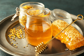 Tray with honey and bee pollen on dark background, closeup