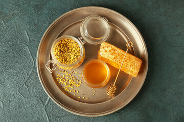 Tray with honey and bee pollen on dark background